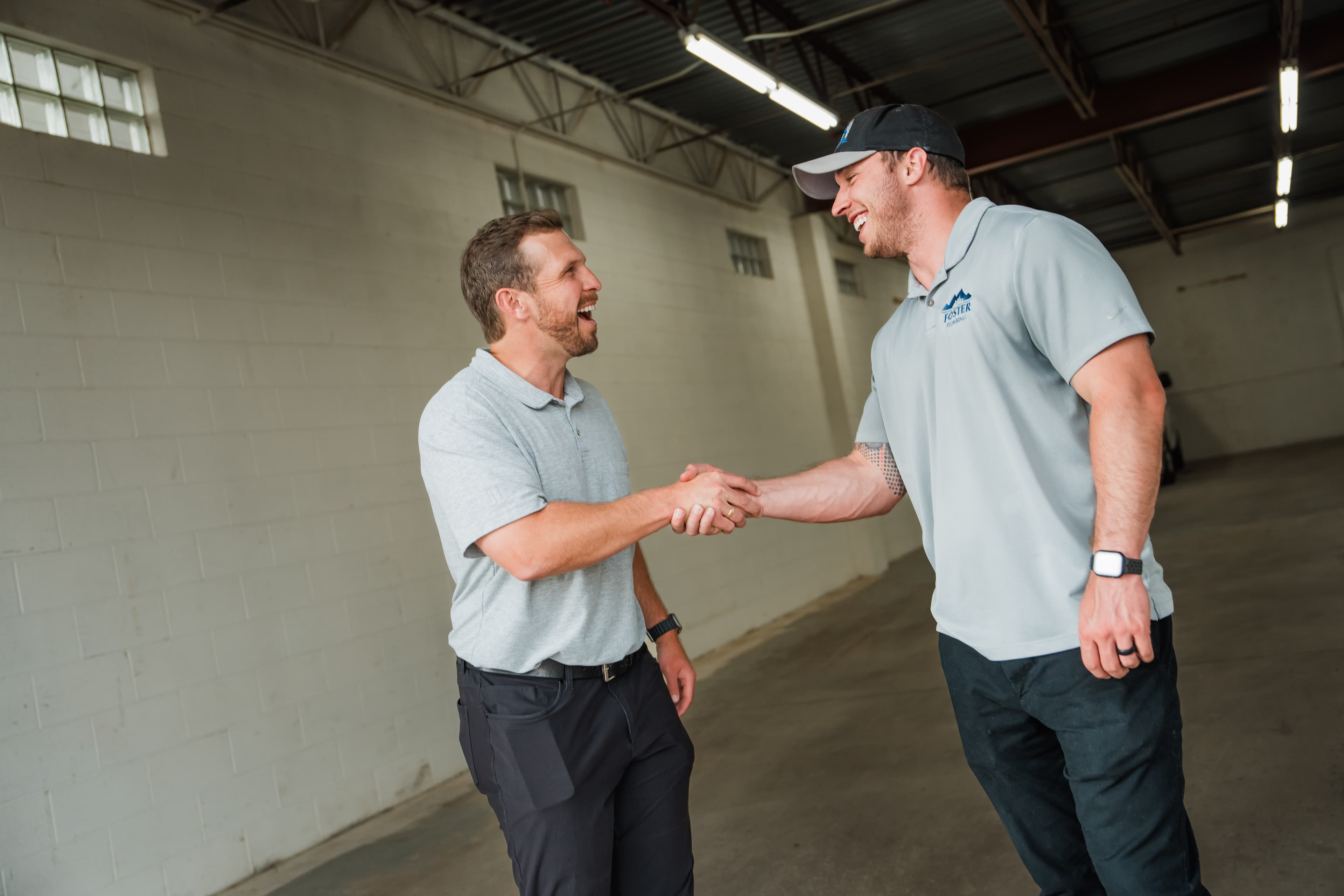 Two people shaking hands inside an empty warehouse bay
